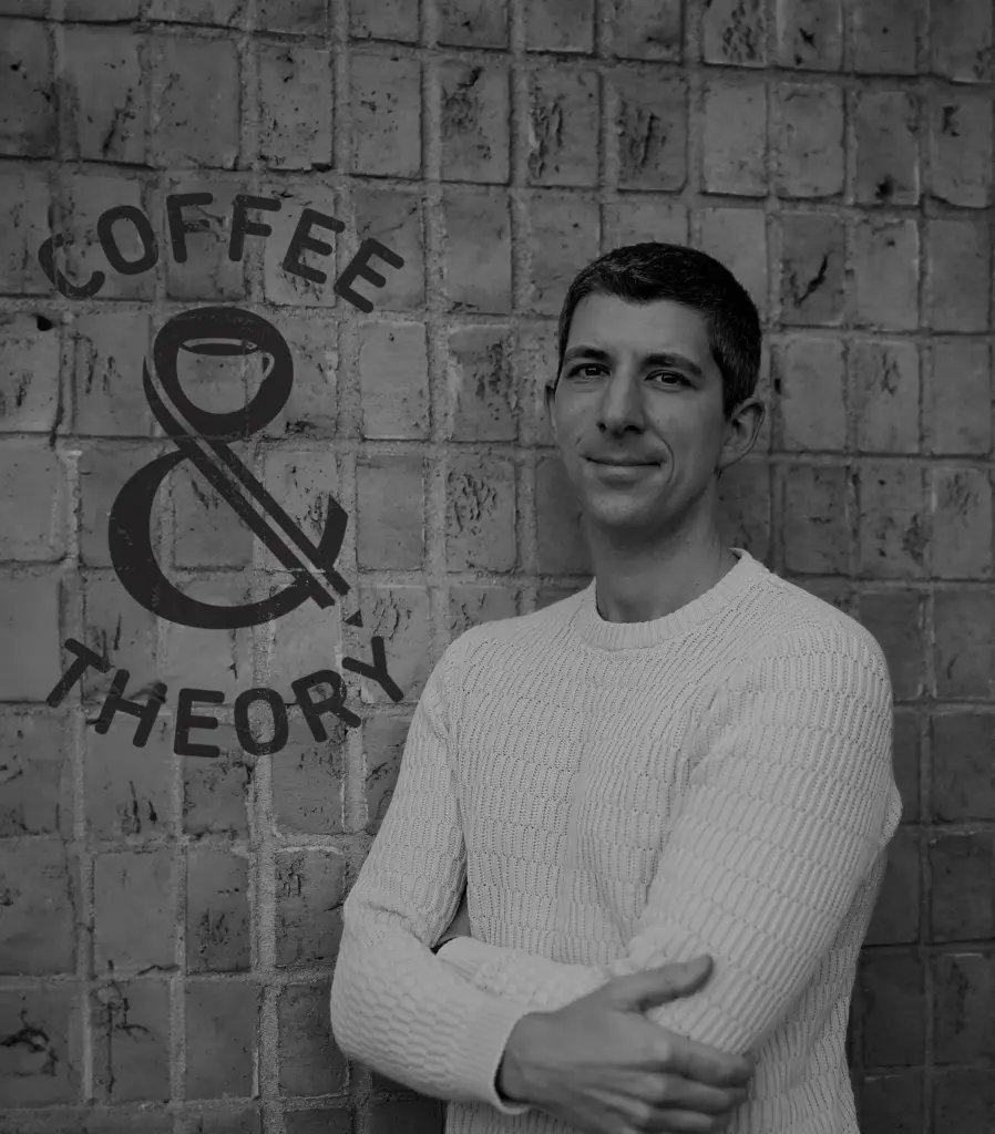 photo of Dr Will Zoppellini in front of a wall with Coffee & Theory Logo