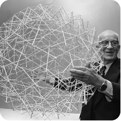 Man holding a large geometric sphere made of rods and connectors.
