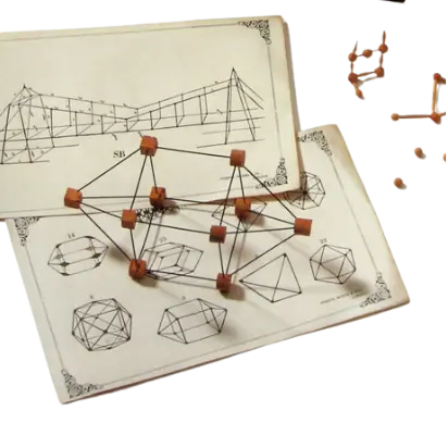 Geometric structure model with wooden connectors placed on architectural drawings.
