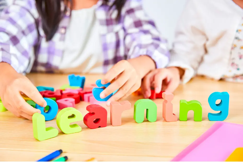 Children arranging colorful letters to spell learning