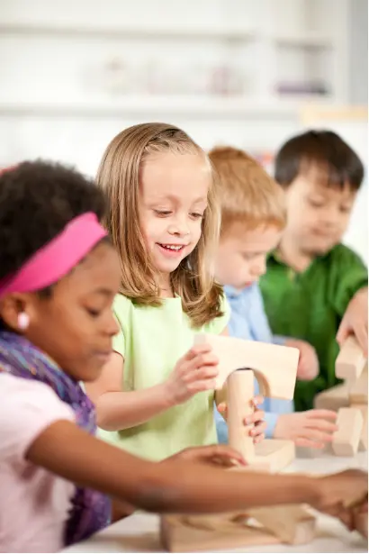 Children building with wooden blocks during a classroom play activity.