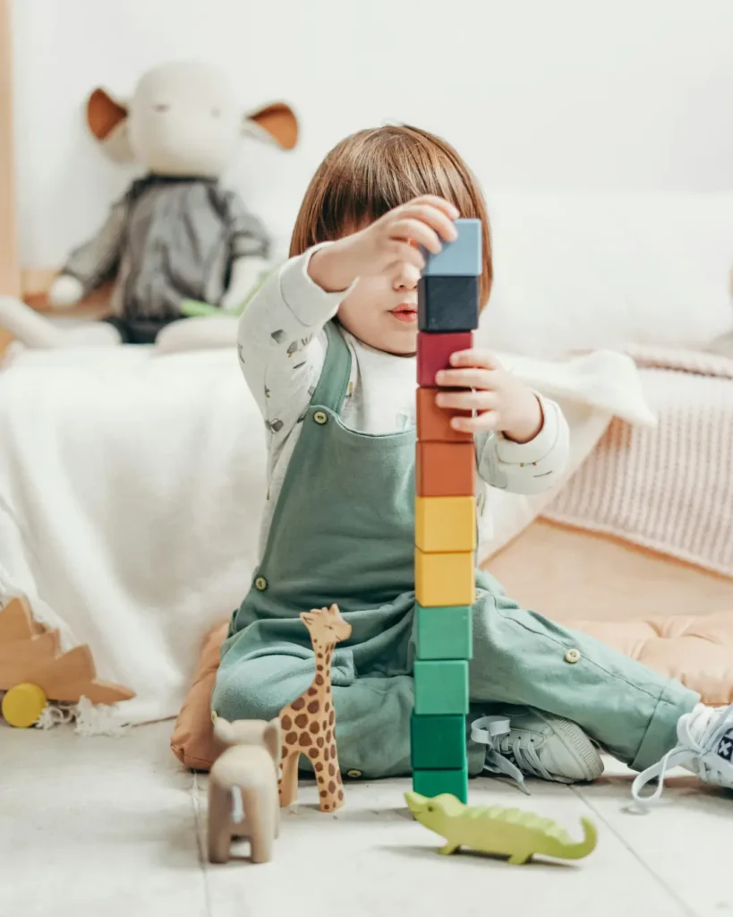 Young child stacking wooden blocks during play, showing learning through exploration and trial.