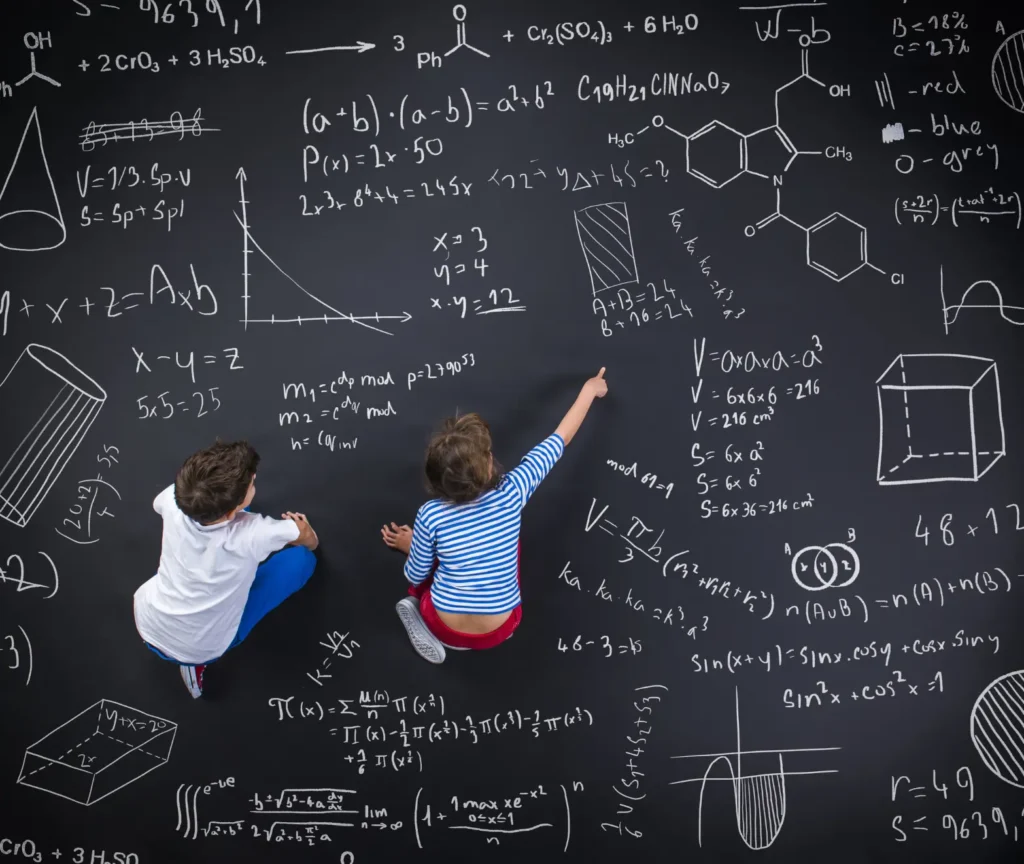 Two children sitting on the floor drawing mathematical formulas and diagrams on a large chalkboard, illustrating curiosity, learning, and cognitive development.