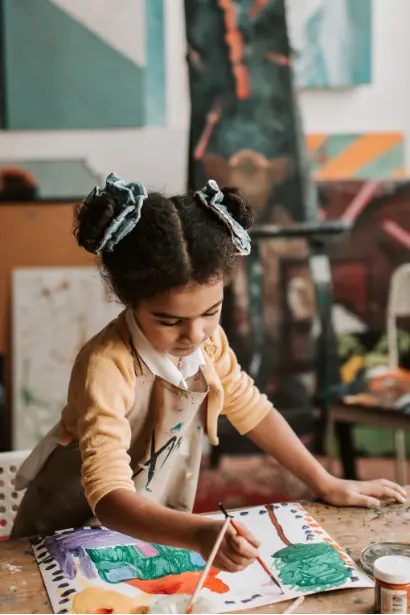 Young child painting at a table, expressing creativity while developing fine motor skills and cognitive flexibility.