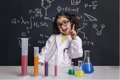 Young girl in a lab coat conducting a science experiment with colorful liquids, showing curiosity and early scientific thinking.