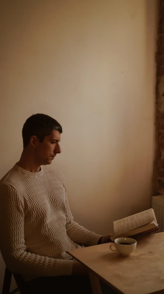 Person reading a book with a cup of coffee, representing learning, reflection and curiosity